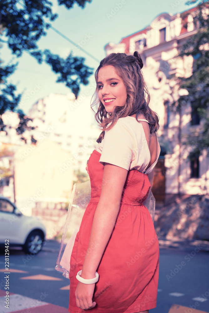 Fototapeta premium Open back. Appealing dark-eyed woman wearing dress with open back smiling broadly while enjoying her amazing weekend