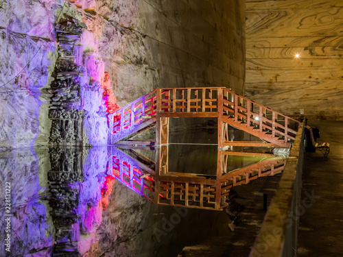 Illuminated stalactites from salt and wooden bridge across the reservoir in salt mines in Slanic - Salina Slanic Prahova -  in the town of Prahova in Romania. photo