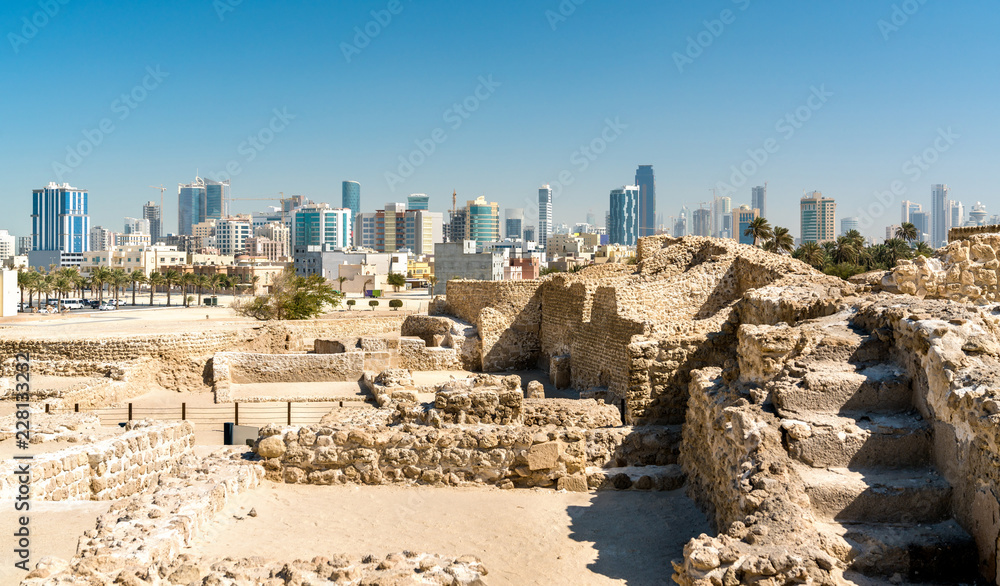 Naklejka premium Ruins of Bahrain Fort with skyline of Manama. A UNESCO World Heritage Site