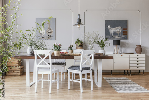 Real photo of a rustical dining room interior with a wooden table, chairs and plants photo
