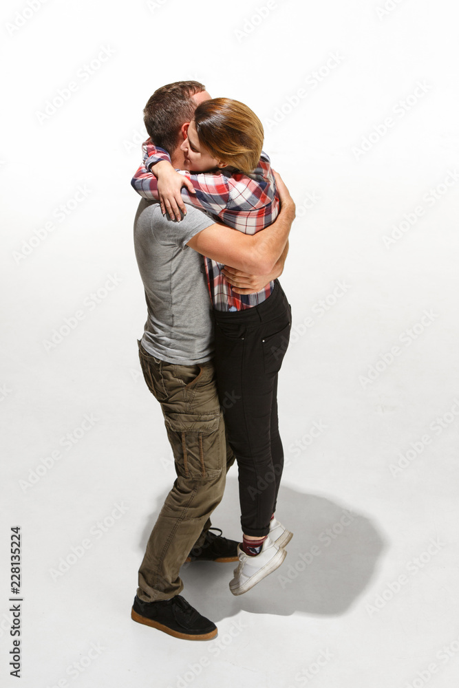 Full body portrait of hugging couple. Caucasian models in love, relationship, dating, flirting, lovers, romantic concept on white studio background. Hugging day concepts Full body portrait of hugging couple. Caucasian models in love, relationship, dating, flirting, lovers, romantic concept on white studio background. Hugging day concepts