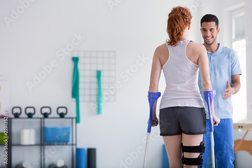 Patient with crutches during a rehabilitation with her physiotherapist in a clinic
