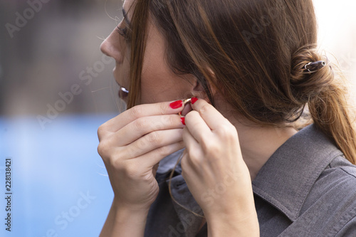 Young woman putting on earring photo