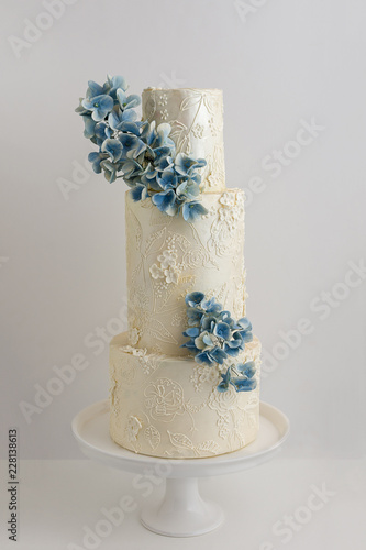 Elegant 3 Tier Wedding Cake With Piped Lace Accents And Edible Floral Bouquet.