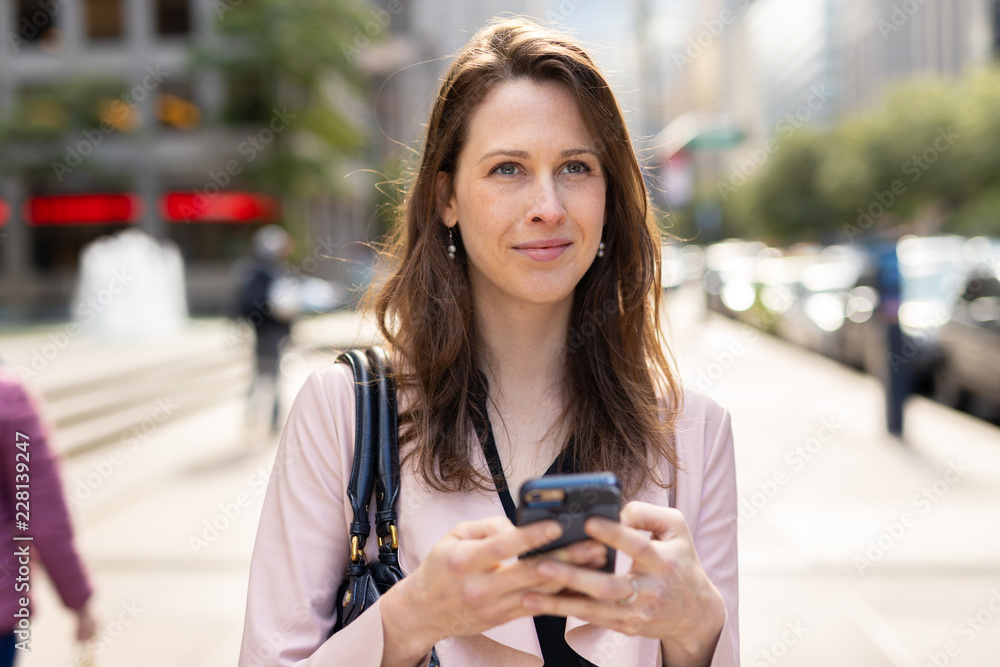 Fototapeta premium Business woman in city walking using cell phone