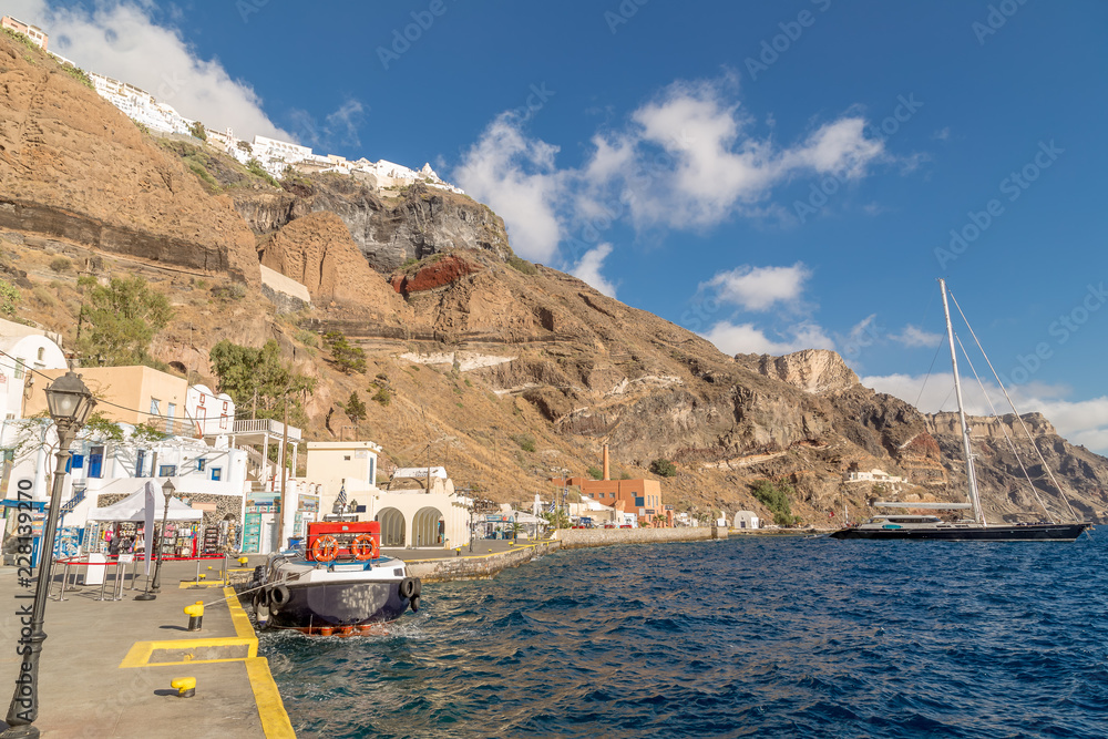 Obraz premium FIRA, SANTORINI, GREECE - JUNE 10, 2017: Tourists and tourist ship in the old port in Fira, Santorini