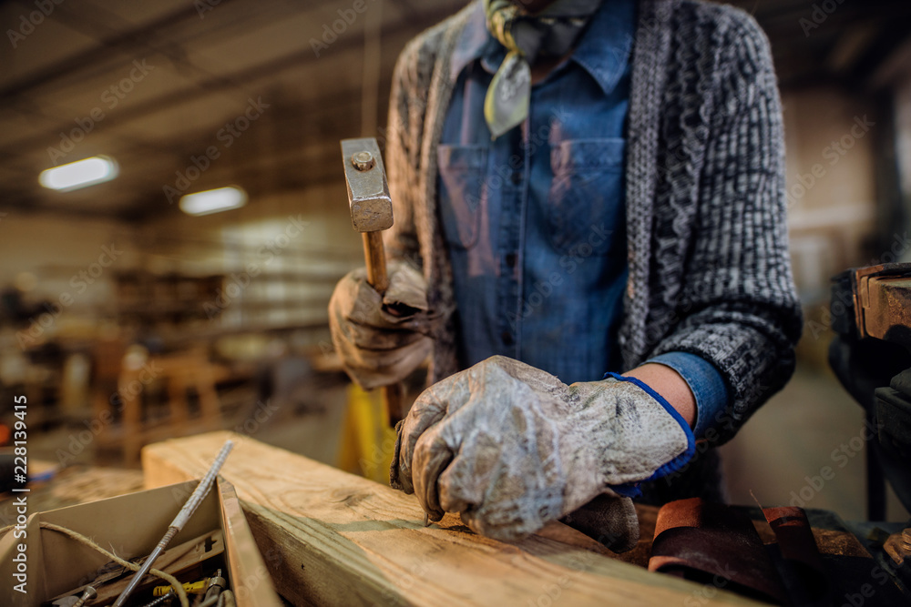 Woman nailing nails in carpentry workshop. Close up of hands. Woman nailing nails in carpentry workshop. Close up of hands.