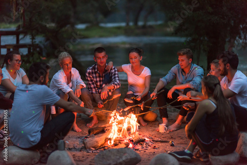 Photos young friends relaxing around campfire