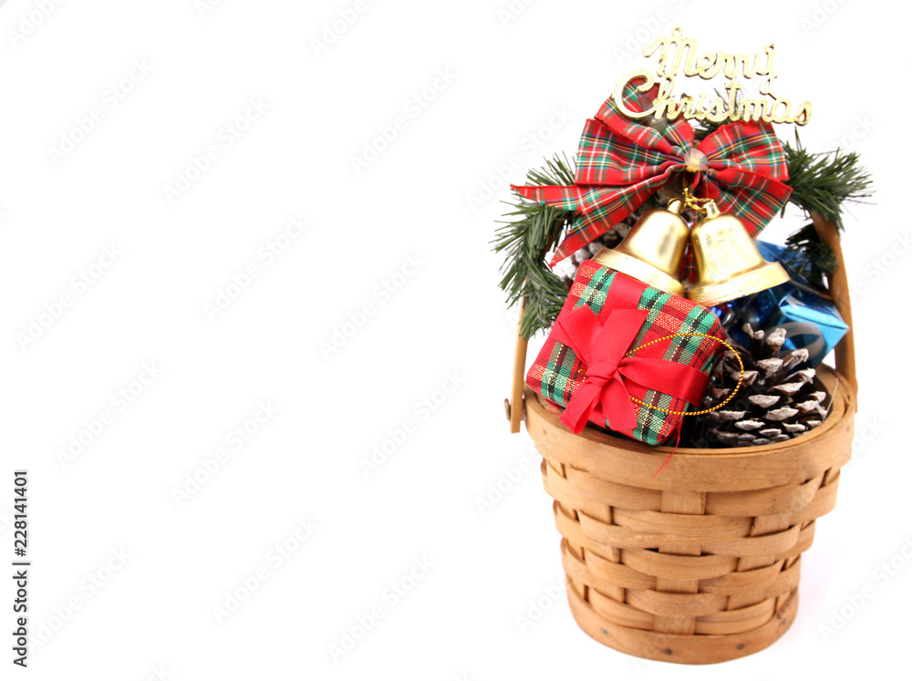 Gifts and decorations in a basket on Christmas Eve with white backdrop.