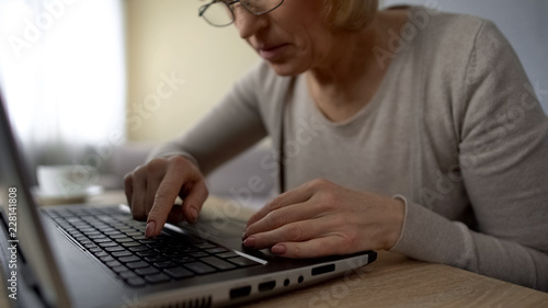 Quadro su tela Elderly lady looking for key on laptop at home, computer courses online training