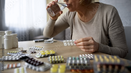 Bild auf Leinwand Senior lady obsessed with healthcare drinking too much pills medication overdose
