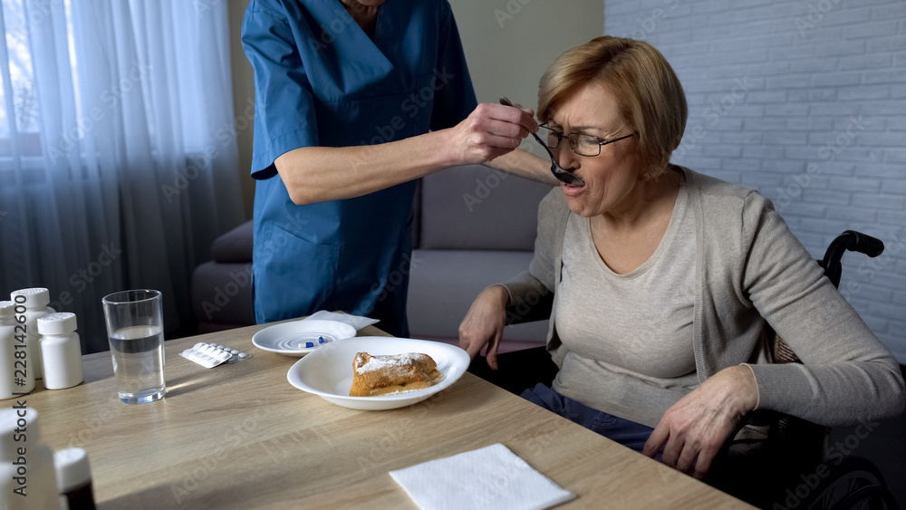 Nurse feeding old disabled female in wheelchair medical support and care sadness Nurse feeding old disabled female in wheelchair medical support and care sadness