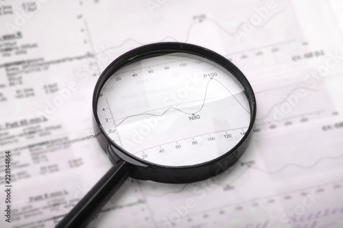 Classic black magnifying glass lying on a medical chart and graph