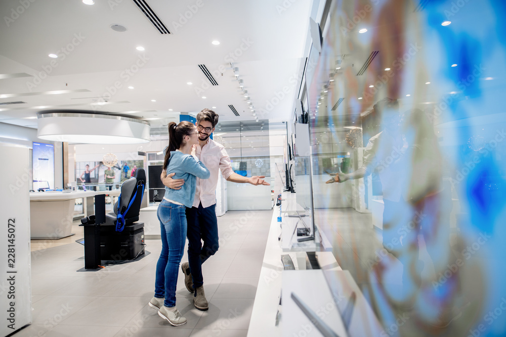 Couple looking for new TV to buy. New technologies concept. Couple looking for new TV to buy. New technologies concept.