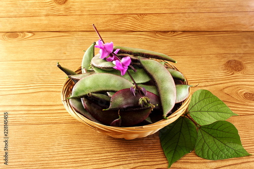  red purple indian surti,valor papdi beans,Hyacinth bean,Lablab purpureus with flower and leaves in basket on wooden background