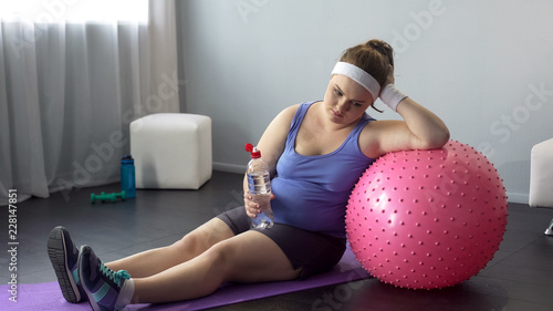 Slika na platnu Fat lady depressed about her weight unsuccessful workout restoring water balance
