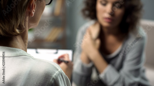 Female psychologist listening to young lady during personal session, depression photo