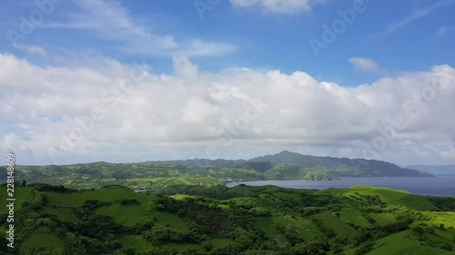 Green hills by the ocean below thick clouds in Batanes, Philippines - High view photo