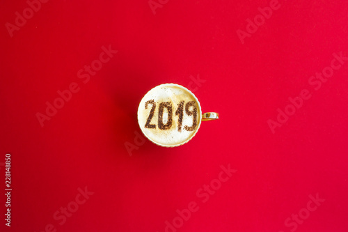 New Year 2019 is written on a cup of coffee with milk. The concept of the new year on January 1. On a red background. Top view, flat lay