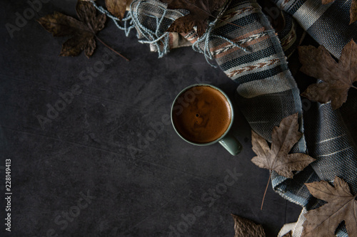 Autumn accessories composition,Autumn leaves,Cup of Coffee,Blanket,Scarf stacked on black background.Flat lay.Autumn objects background.