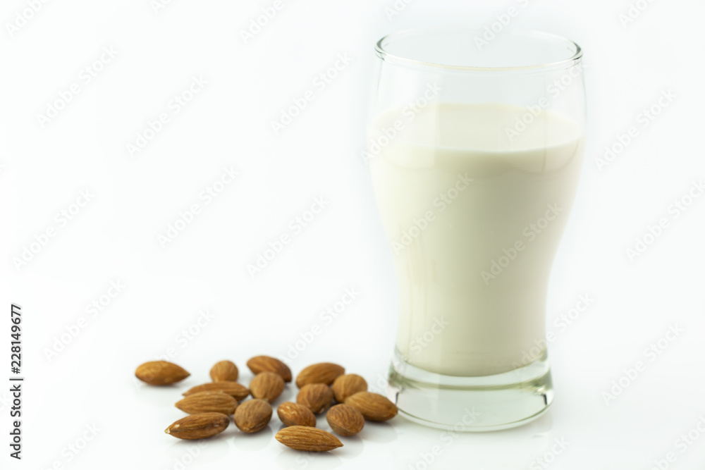 Almond milk in glass with almonds seed on white background Almond milk in glass with almonds seed on white background