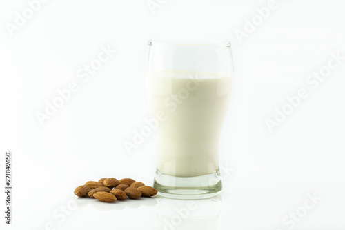 Almond milk in glass with almonds seed on white background