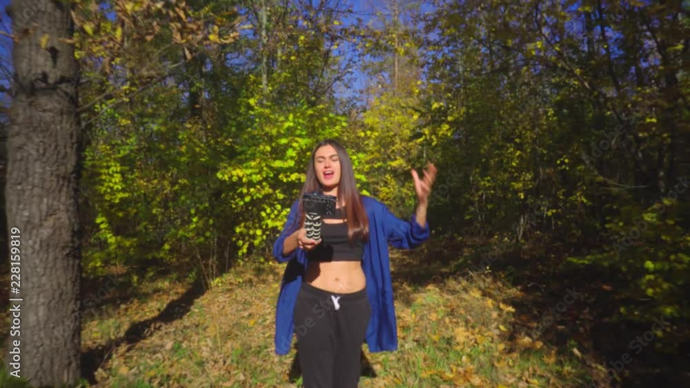 Brunette young woman blogger going in forest and recording video for vlog using camera Brunette young woman blogger going in forest and recording video for vlog using camera