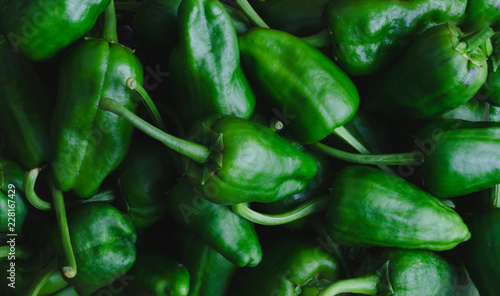 Green peppers in tray on dark wooden background.