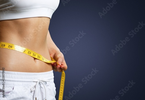 Slim young woman measuring her thin waist photo