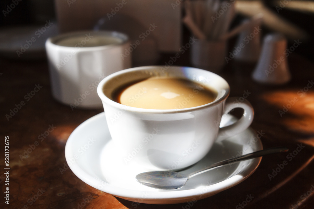 white cup with coffee in the morning rays of the sun white cup with coffee in the morning rays of the sun
