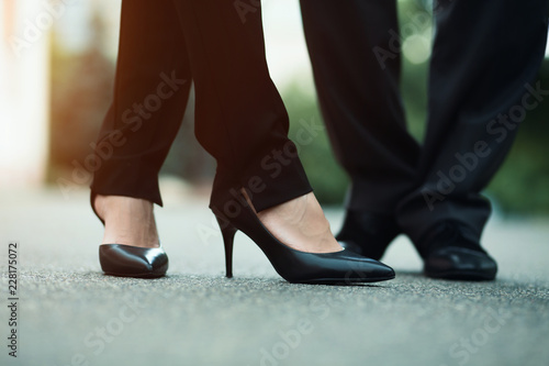 Closeup of businessman's and businesswoman's legs outside. Standing on the street.