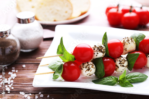 Sticks with mozzarella  tomatoes and basil leafs on wooden table