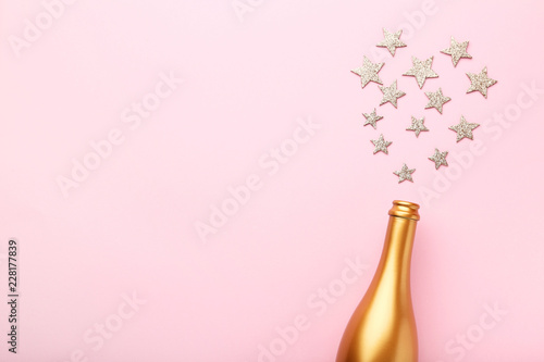 Decorated champagne bottle with stars on pink background