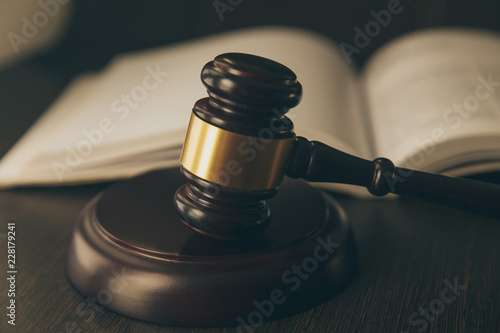 Law concept - Open law book with a wooden judges gavel on table in a courtroom or law enforcement office on blue background. Copy space for text