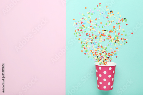 Pink paper cup with confetti on colorful background