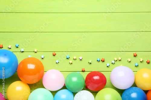Colorful balloons with paper stars on green wooden table
