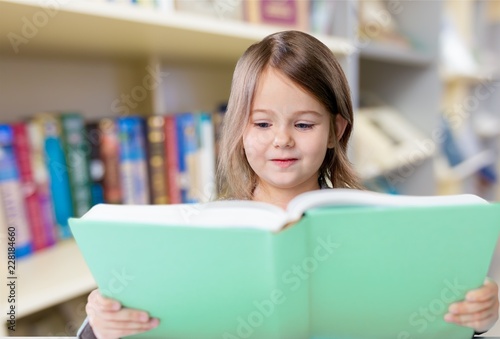 Adorable young girl reading a book