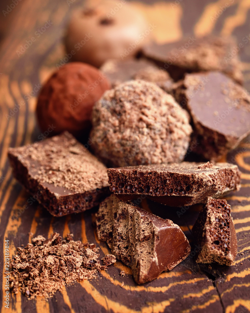Handmade chocolate candies and pieces of chocolate on wooden background Handmade chocolate candies and pieces of chocolate on wooden background