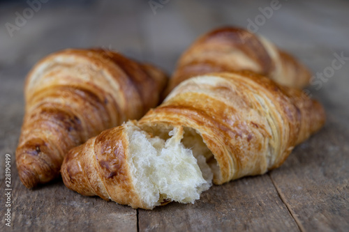 Tasty well-baked croissant on a wooden kitchen table. Light bread prepared for breakfast.