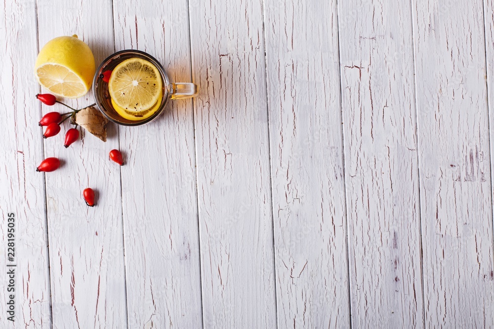Treating cold. Hot tea with lemon and berries stands on white wooden table Treating cold. Hot tea with lemon and berries stands on white wooden table