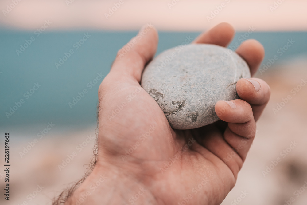 Smooth stone closeup in hand on the background of the sea, sea pebbles Smooth stone closeup in hand on the background of the sea, sea pebbles