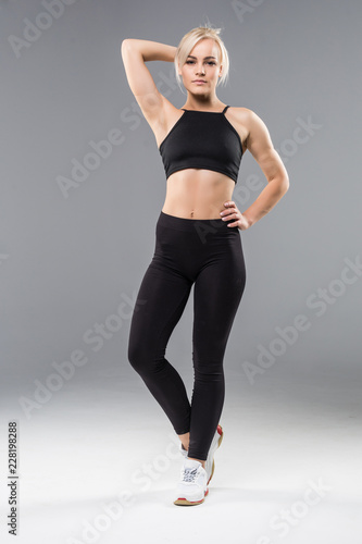 Portrait of a smiling fitness woman stretching her hands isolated over gray background