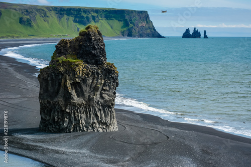 Rocks formation on Dyrholaey cape with black sand beach and puffins near Vik town, Iceland in summer on sunny day