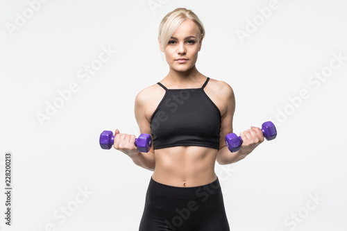 portrait of pretty sporty woman holding weights isolated on gray background