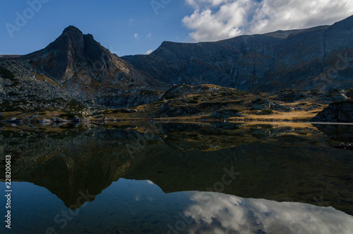 Mind blowing mirror like lake reflections . Lake Bliznaka (The Twin) one of a group of glacial lakes in the northwestern Rila Mountains in Bulgaria. Autumn 2018 photo