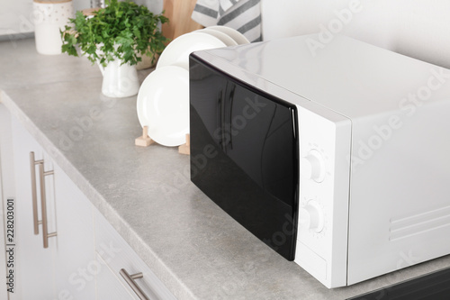 Modern microwave oven on table in kitchen