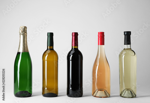 Bottles with different types of wine on light background