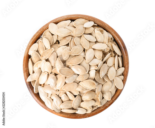 Bowl with raw pumpkin seeds on white background, top view