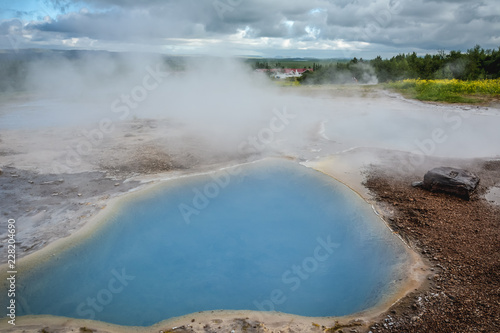 Geyser Park in Iceland - holes in the ground filled with hot water with steam coming from them