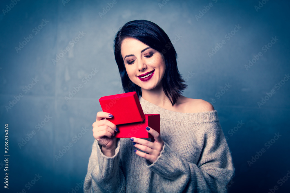 Portrait of a style brunette woman with little red gift box on grey background Portrait of a style brunette woman with little red gift box on grey background